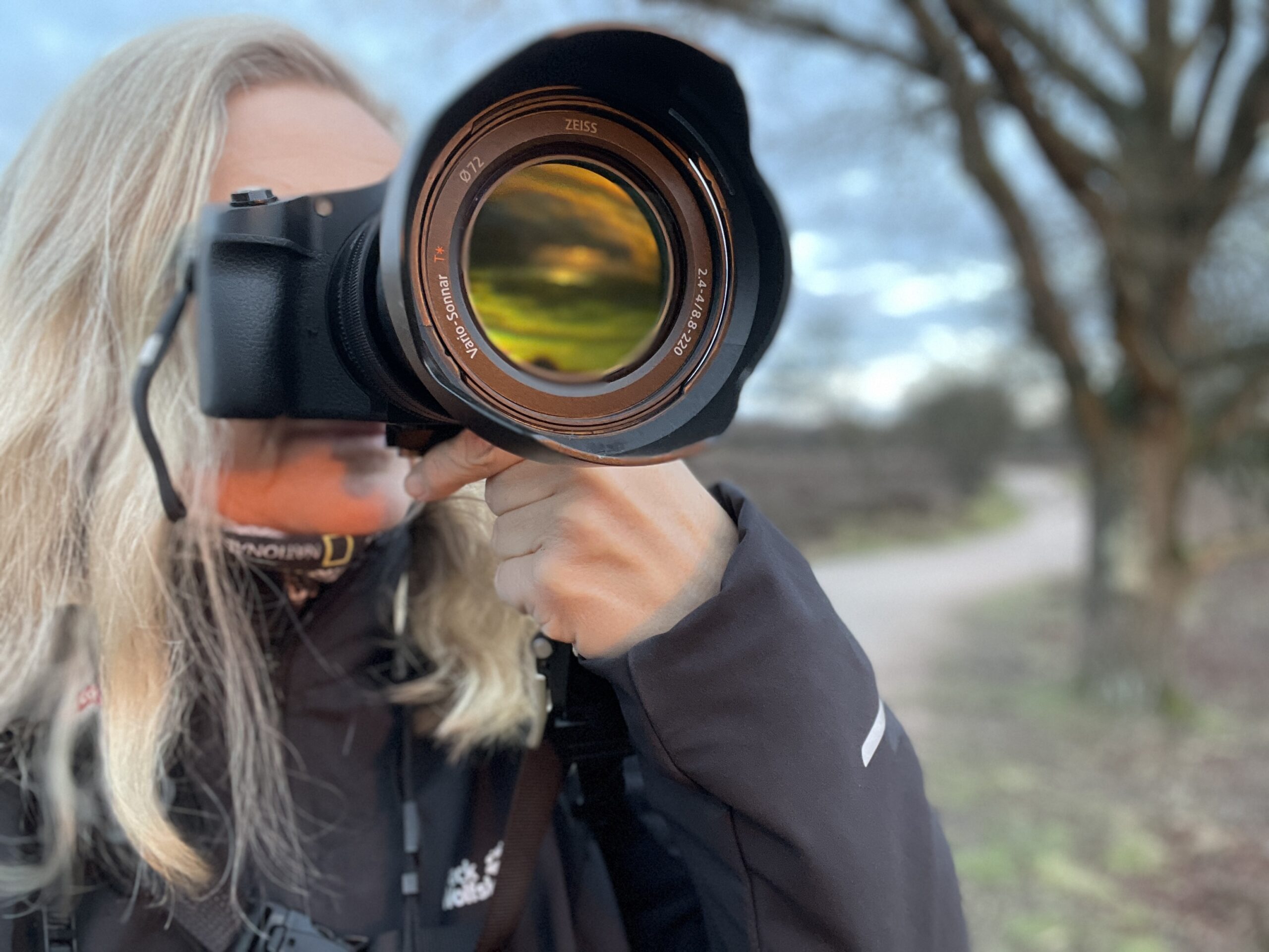 Doortje van Dijk met camera naast het fietspad van de Zuiderheide tijdens zonsopgang.